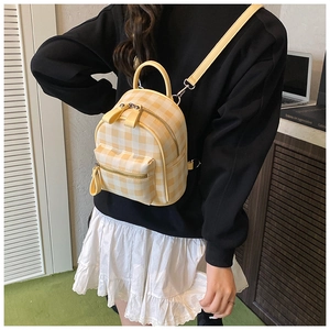 Vue détaillée du mini sac à dos à carreaux jaunes avec fermetures éclair et fines bretelles