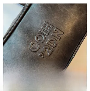 Close-up of deep brown pebbled leather texture with COIH 2DN embossed logo detail