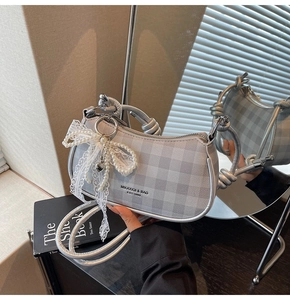 Détail du sac sous l'aisselle à carreaux avec poignée nouée argentée et nœud en perles