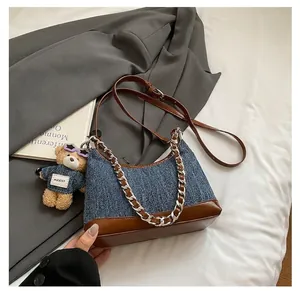 Λεπτομέρεια τσάντας denim και δέρματος με ασημένια αλυσίδα και κρεμαστό αρκουδάκι