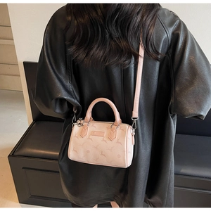 Detailed view of pink Boston bag with elk print worn over a premium black leather coat