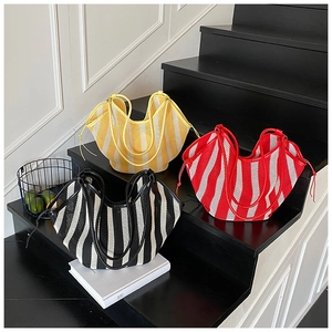Close-up of three woven mesh tote bags with bright stripes on a stylish wooden staircase