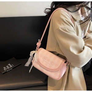 Detail of pink plaid shoulder bag featuring cat embroidery and pearl bow accessory