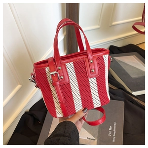Détail d'un sac à main tissé rayé rouge et blanc avec patchwork en cuir et boucle métal