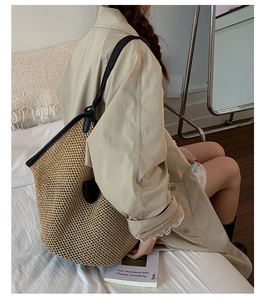 Detail of hand-woven straw tote bag with black leather trim and shoulder strap