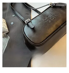 Detail of black matte leather shoulder bag with embossed COIH 92DN text and silver buckle