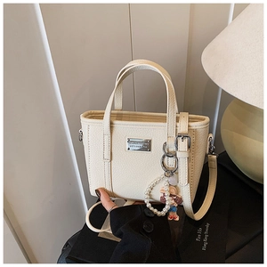 Dettaglio della borsa tote in pelle martellata bianco crema con ciondolo di perle e metallo