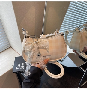 Détail du sac à carreaux beige avec nœud en dentelle et breloques cœur en perles