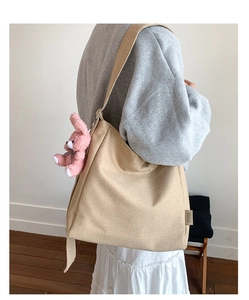 Detail of canvas tote bag with wide strap and cute pink rabbit plush keychain