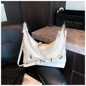 Detail view of white glossy patent leather underarm bag with silver metal buckles on chair