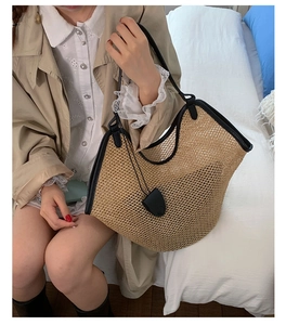 Close-up of a woven straw bucket bag with black leather handles for summer beach style