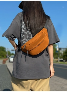 Rear view of a stylish orange-brown chest bag with textured fabric and adjustable strap