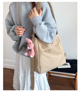 Khaki canvas tote bag detail with pink plush bunny charm and spacious shoulder strap