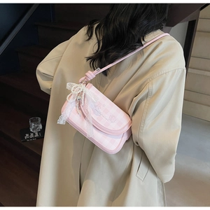 Detailed back view of pink plaid crossbody bag with lace bow on model in tan coat
