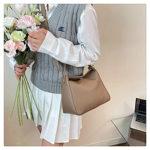 Brown lychee leather tote bag with slim shoulder strap shown in a lifestyle indoor setting