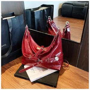 Detail of burgundy glossy leather hobo bag showing wrinkled texture and silver hardware