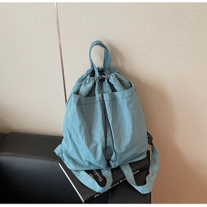 Detail view of a Morandi blue nylon drawstring backpack with adjustable buckle and side pockets