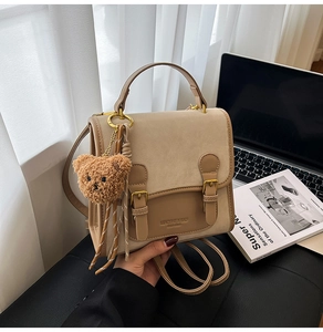 Close-up of beige and brown patchwork bag with metal buckle and plush bear charm