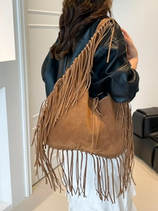 Vintage brown suede tote bag with long bohemian tassels shown on shoulder model