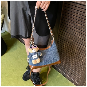 Λεπτομέρεια τσάντας denim hobo με δερμάτινη επένδυση και γούρι αρκουδάκι στον ώμο