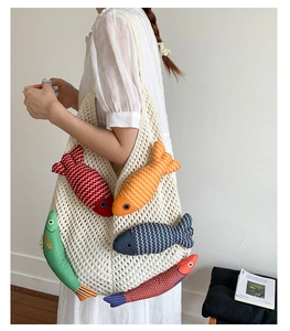 Detail of hand-woven beige crochet tote bag with colorful decorative fish charms