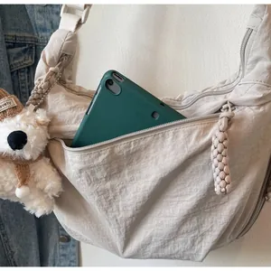 Detail of large nylon moon bag showing spacious interior with iPad and woven zipper pull