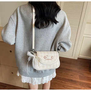 Detail view of beige checkerboard bag with lace bow and pearl pendant accessories