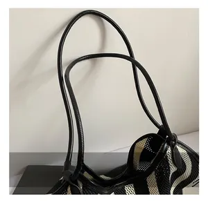 Detail of woven tote bag with black and white zebra stripes and leather handles