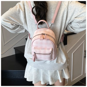 Rear view of a girl wearing a pink plaid mini backpack with silver zipper details