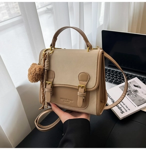 Detail of khaki leather vintage satchel showing the embossed brand logo and metal hardware