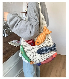 Detail of knitted tote bag featuring 3D colorful plush fish toys on a beige crochet net