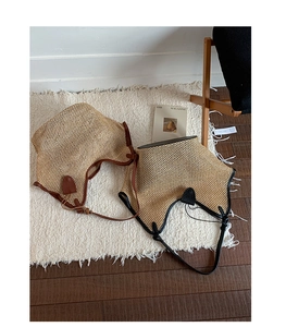 Detailed texture of woven straw beach tote bag with premium leather trim and slim strap