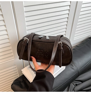 Close-up of deep brown Boston bag showing embossed COIH 2DN logo and silver hardware