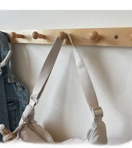 Detail of beige nylon crescent bag with adjustable wide strap and cute bear charm