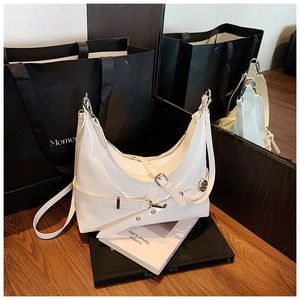 Detailed shot of white patent leather underarm bag with silver buckle on a wooden surface