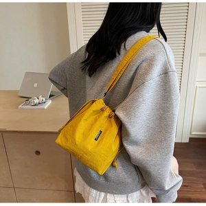 Detail of yellow drawstring bucket bag with branded label and premium nylon texture