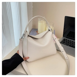 Detail of cream lychee texture leather handbag with adjustable strap and silver hardware