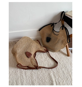 Detailed macro view of large hollow weave straw tote bags with leather trim and charms
