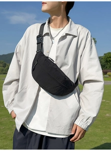 Detail of black nylon belt bag with adjustable strap and buckle against nature backdrop
