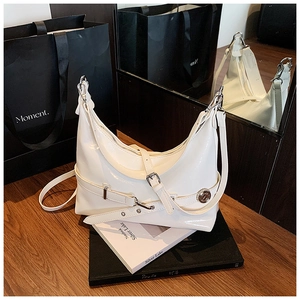 Detail shot of white glossy underarm bag with silver buckles on a wooden surface