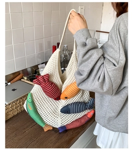 Detail of crochet tote bag with colorful fish charms in a modern kitchen setting