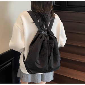 Rear view of a minimalist black waterproof drawstring backpack with textured fabric