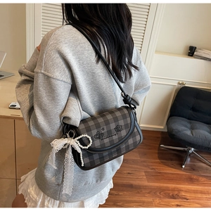 Close-up of checkered saddle bag with cute embroidery and pearl lace keychain