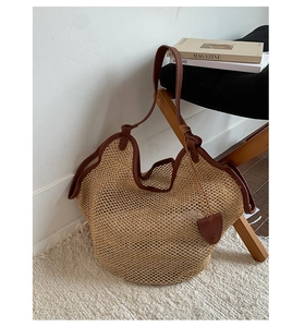 Detail view of woven straw tote bag with brown leather handles on a chair