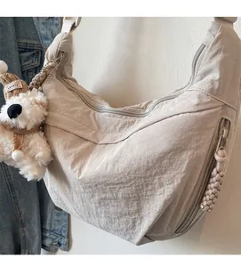Detail of beige nylon crescent bag featuring a cute teddy bear plush charm with Lovely tag