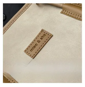 Detail of grey suede fabric with brown leather patch and embossed miao & she logo