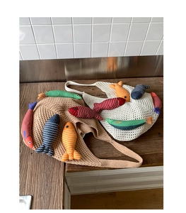 Detail of colorful knitted fish charms with embroidery inside woven mesh tote bags