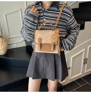 Detail of vintage beige canvas backpack with brown leather straps and plush bear charm