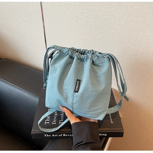 Detailed view of the light blue drawstring bucket bag with branded woven label and fabric texture