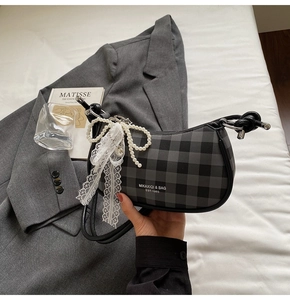 Détail du sac à bandoulière à carreaux avec perles élégantes et nœud en dentelle